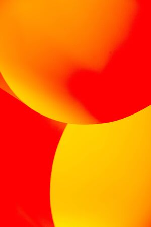 an abstract macro photo of curve shapes made up of paper, coloured in yellow and redの写真素材