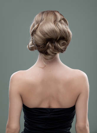 a head and shoulders image of a young woman, from the back. her hair is long and blonde and she is showing an interesting, wavy hairstyle.の写真素材