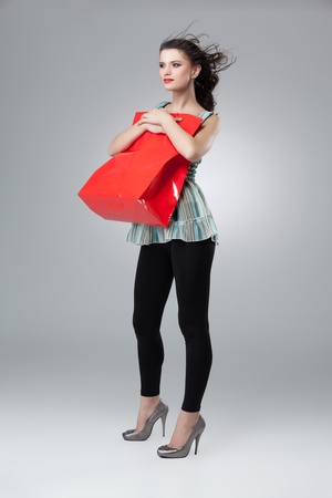 tall brunette woman holding red shopping bag の写真素材