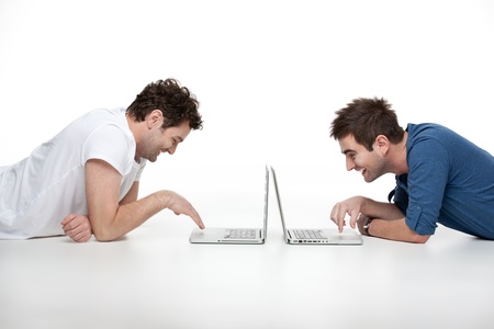 young  men looking and laughing at laptopsの写真素材
