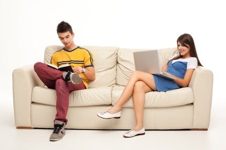 young couple sitting comfortable with book and laptopの写真素材