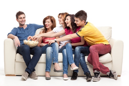 friends sitting on couch reaching for the popcorn bowl の写真素材