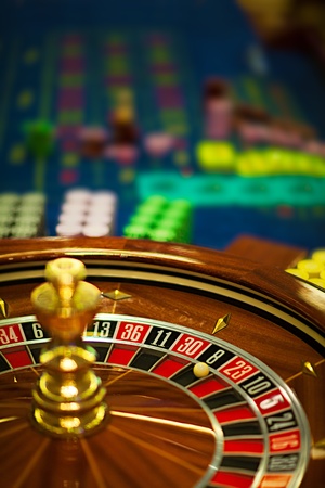 closeup of a wooden roulette wheel, with betting chips behind の写真素材
