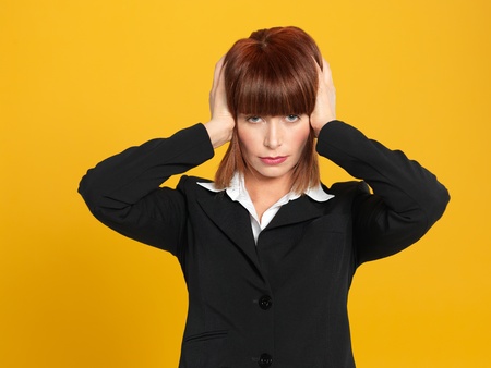 portrait of a beautiful, young, stressed businesswoman, having a head ache, on yellow backgroundの写真素材