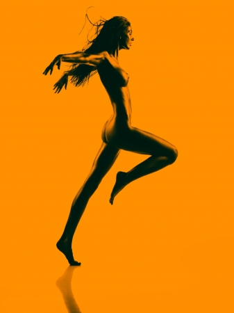 artistic nude of a young woman with black painted skin and orange background, jumping forwardの写真素材