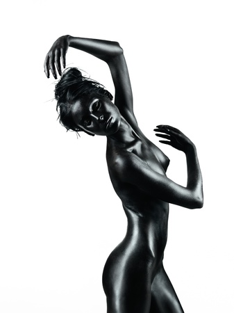 artistic nude of a young woman with black painted skin,isolated on white background, in a dance movementの写真素材