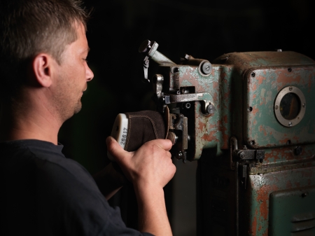 adult man working in a shoe factory, sewing the soles of the shoes, at a machineの写真素材