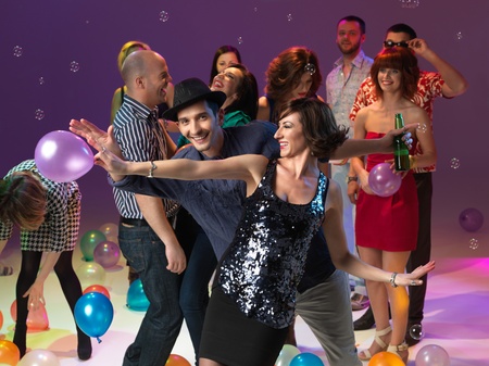 couple dancing and smiling, together with friends, on colored backgrpund, with bubbles and balloons
