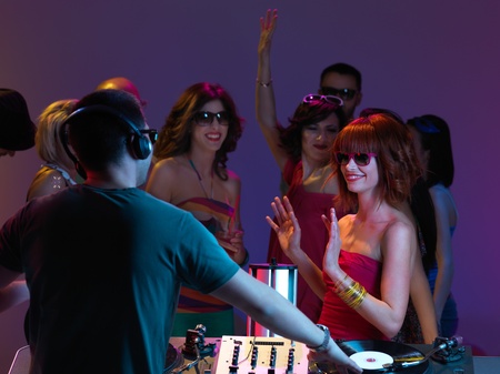 girls looking at dj and dancing, with sunglasses on, with other people partying in the backgroundの写真素材