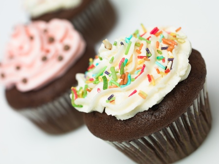 Chocolate muffins with icing and colorful sprinklesの写真素材