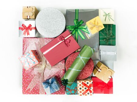 a pile of different shaped presents wrapped in shiny paper, with colorful bows, isolated on white backgroundの写真素材
