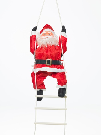 closeup of happy toy santa climbing a plastic and rope ladder isolated on whiteの写真素材