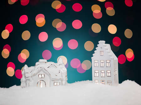 closeup of two white porcelain trinkets with golden lines surrounded by snowflakes on colorful christmas lights backgroundの写真素材