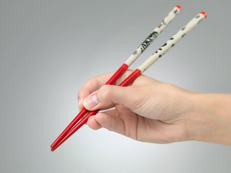 closeup of female hand holding chopsticks on grey gradient backgroundの写真素材