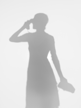 young girl silhouette talking on vintage phone behind diffuse surface