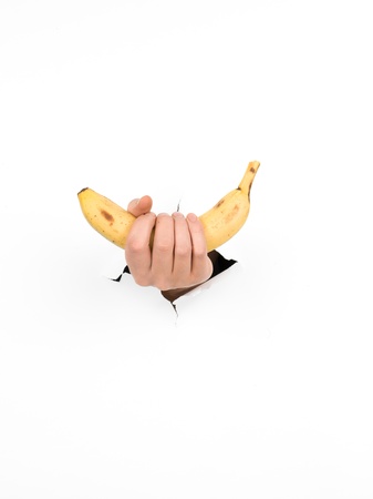 close-up of male hand holding a banana through a torn white paper, isolatedの写真素材