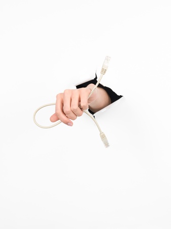 close-up of female hand holding a network cable through a torn white paper, isolated