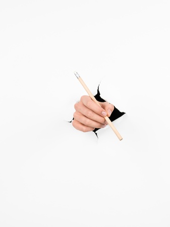 close-up of female hand holding a pencil through a torn white paper, isolated