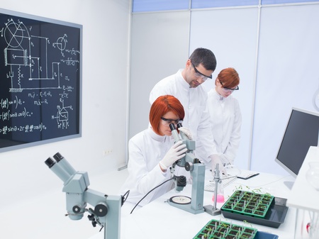 general-view  of a specialist teaching and supervising two women in a chemistry lab around a...