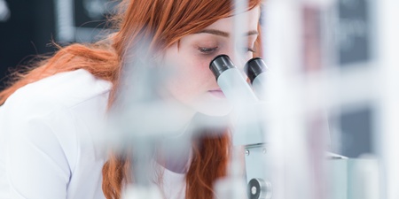 blurred macro-view of a student in a chemistry lab analyzing under microscopeの写真素材