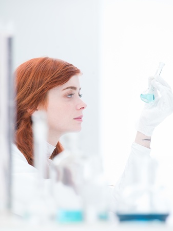 side-view of a student in a chemistry lab analyzing colorful liquidsの写真素材