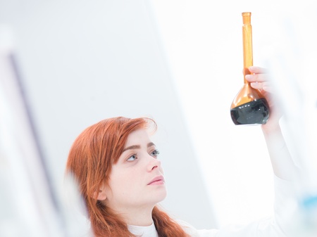close-up of a beautiful girl student in a chemistry lab analyzing colorful substancesの写真素材