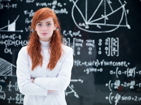 close-up of schoolgirl succesful looking  in the camera in a chemistry lab with a blackboard on the...