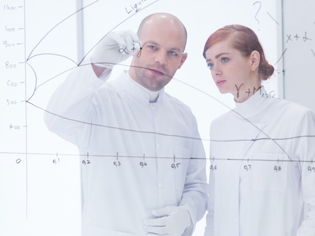 general-view  of a teacher in a chemistry lab drawing and writing formulas  on a transparent board for his studentの写真素材