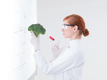 side-view  of one beautiful student injecting a broccoli in front of a whiteboardの写真素材