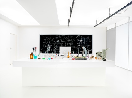 general-view of a chemistry laboratory with a lab table containing colorful liquids and lab tools and a blackboard on the backgroundの写真素材