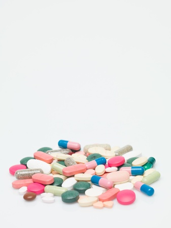 A group of different kind of pills isolated on white background. The colors of the medicines are in different touches of white, green, brown, grey, blue, pink, orangeの写真素材