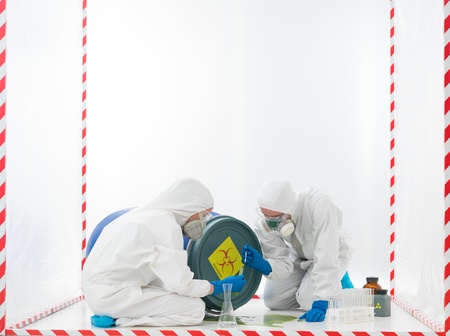 specialists collecting samples from a biohazard accident, in a cube surrounded with red and white tapeの写真素材