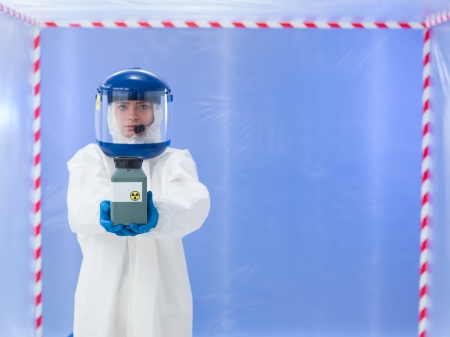 female scientist wearing white protection suit and blue mask, holding a toxic waste container
