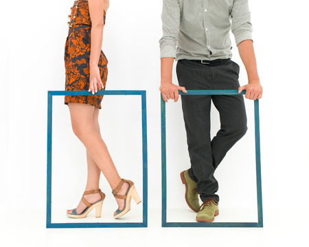 cropped view of man and woman legs behind two empty framesの写真素材