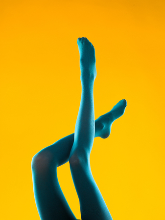 cropped view of female legs in blue stockings on yellow backgroundの写真素材