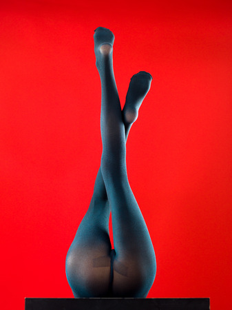woman wearing pantyhose lying on her back with her feet up on red backgroundの写真素材