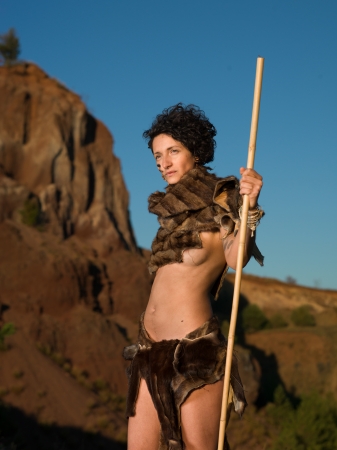 cropped view of beautiful caucasian woman wearing fur handmade tribal clothes, holding a spear in natureの写真素材