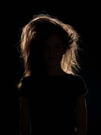 front view of woman with tousled hair in black shadow, n black backgroundの写真素材