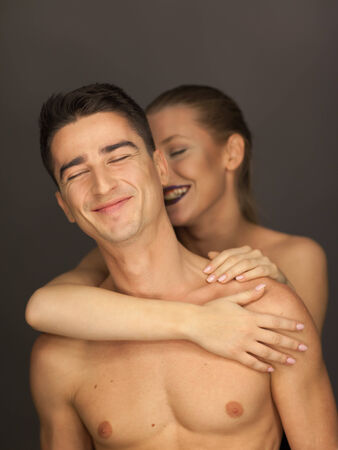 beautiful couple in studio portrait front view pose for the camera, the woman behind smileの写真素材