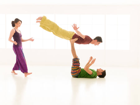 Three young people a woman and two men practice yoga partner in class on background window の写真素材