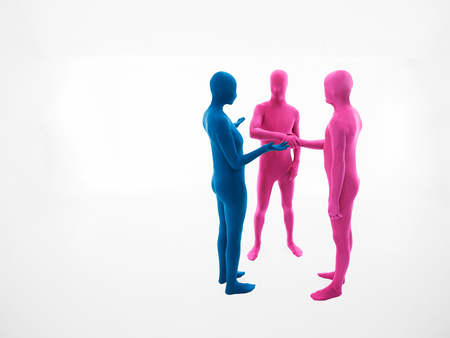 a woman dressed in blue suit persuades two men dressed in pink to raise shake handsの写真素材