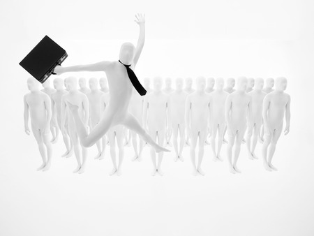white businessman with tie and black briefcase jumping in front of a group of lined peopleの写真素材