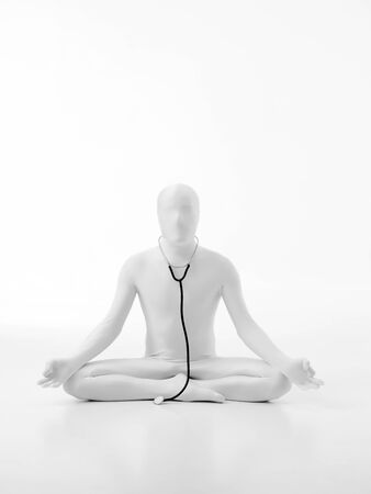 faceless man dressed white with stethoscope hanging from his neck in yoga lotus positionの写真素材