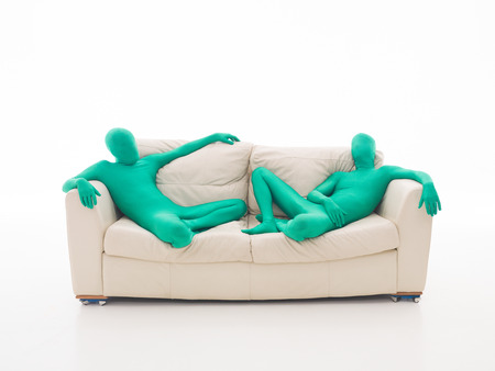 Two green men, faceless, sitting lazy couch の写真素材