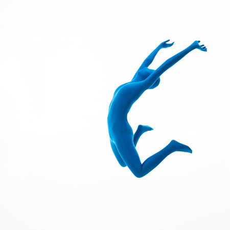 Woman dressed in blue suit jumps up on white の写真素材