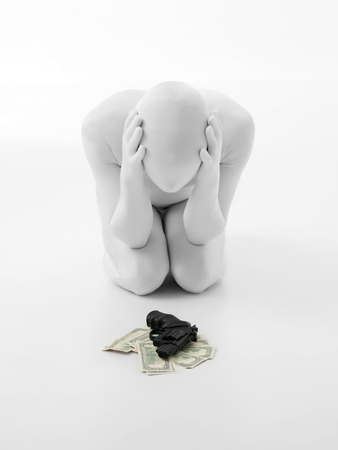 faceless man dressed in white hopeless thinks will certainly use a gun sitting on a pile of money の写真素材