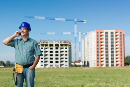 front view of happy caucasian engineer talking on phone at construction siteの写真素材