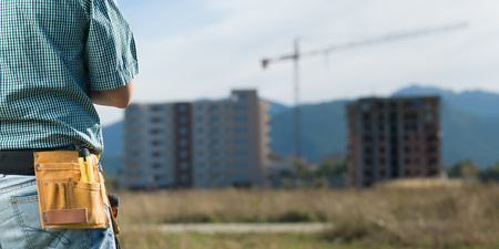 closeup, back view of male engineer standing looking at building in constructionの写真素材