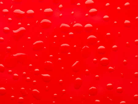 macro of water drops on red surfaceの写真素材
