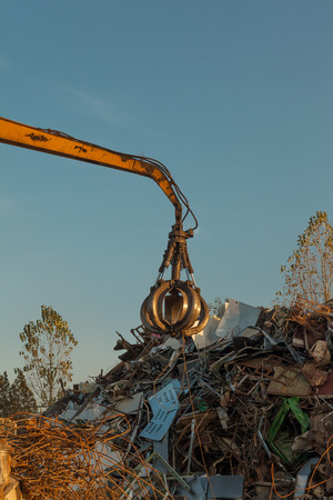 crane holding scrap metal on top of pile of junkの写真素材